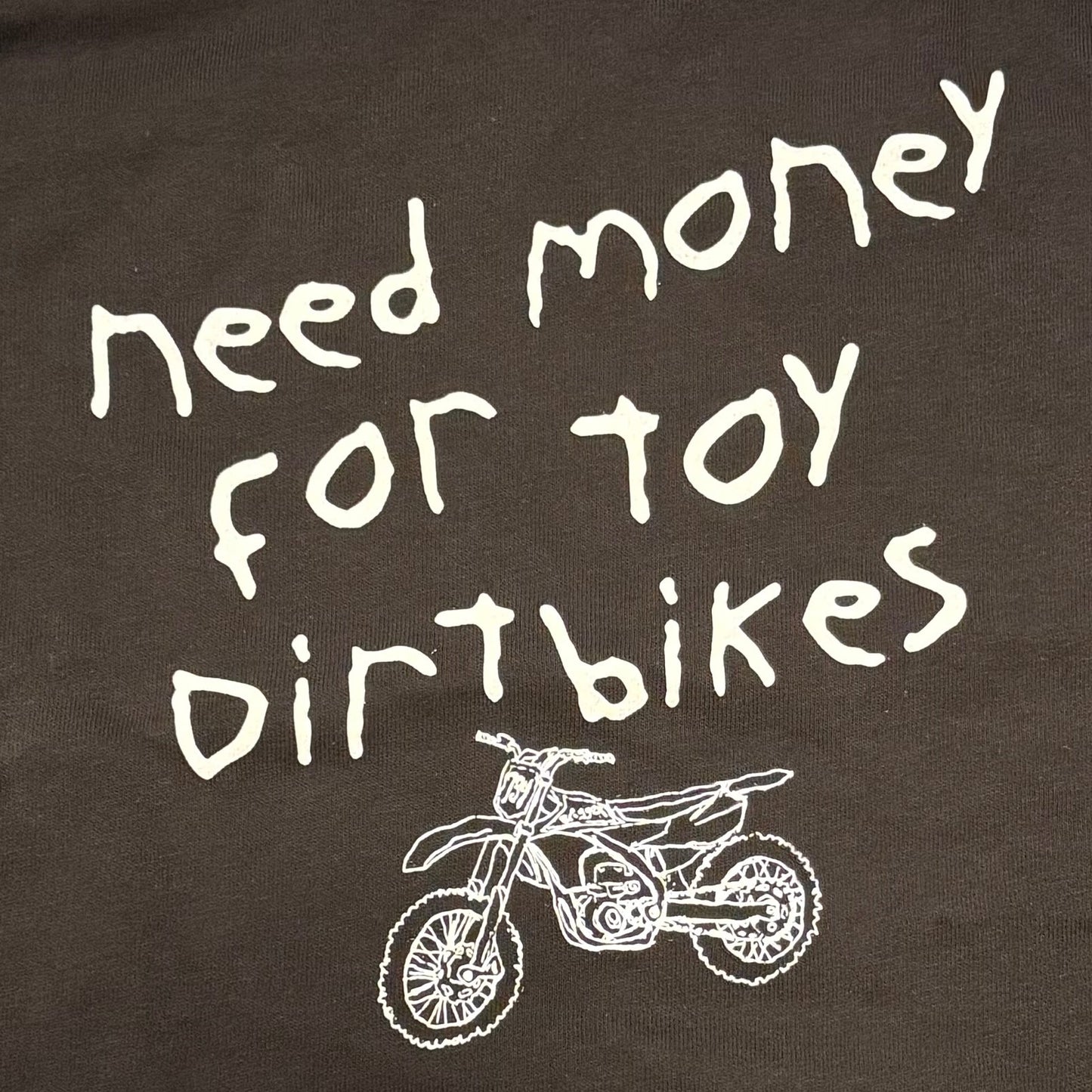 Close up of motocross toddler/youth tshirt Need Money for Toy Dirtbikes with a drawn sketched image of a toy dirtbike with a 734 number plate and Briggzy on the graphics