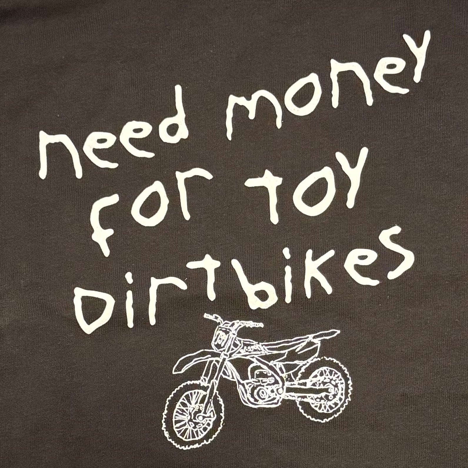 Close up of motocross toddler/youth tshirt Need Money for Toy Dirtbikes with a drawn sketched image of a toy dirtbike with a 734 number plate and Briggzy on the graphics
